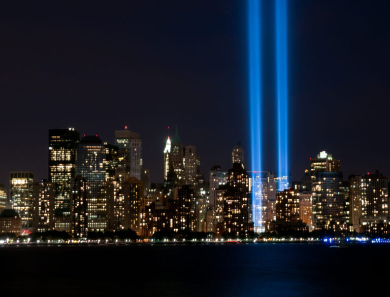 Two blue Tribute in Light beams rising over the New York City skyline at night in remembrance of September 11